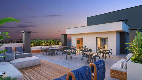 Lounge do rooftop: sofás e mesas ao pôr do sol, no alto do prédio (perspectiva artística)